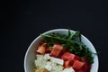 Black background and bowls with healthy, useful kus-kus breakfast with vegetables, tomatoes, mushrooms, arugula and cheese.