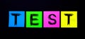 On a black background, bright multicolored stickers with the word TEST. Illustration