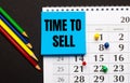 On a black background, a calendar with colored buttons, multi-colored pencils and a blue sticker with the inscription TIME TO SELL Royalty Free Stock Photo