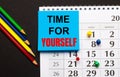 On a black background, a calendar with colored buttons, multi-colored pencils and a blue sticker with the inscription TIME FOR Royalty Free Stock Photo