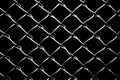 Black background enhances the grid pattern of chain link mesh fence