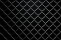 Black background enhances the grid pattern of chain link mesh fence