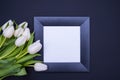 On a black background lies a black frame with a white background and a bouquet of white tulips Royalty Free Stock Photo