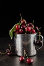 On a black background, a metal cup with cherries with water drops Royalty Free Stock Photo