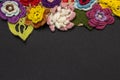 Black background and multicolored knitted flowers on top Royalty Free Stock Photo