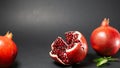 Black background, in the photo there are three pomegranates fruit in the middle of the rosewood and pomegranate grains are visible Royalty Free Stock Photo