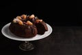 On a black background with a place for writing text on a stand, a chocolate cake is decorated with fruits