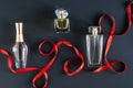 on a black background, a red satin ribbon and three bottles of women\'s perfume. layout. Royalty Free Stock Photo