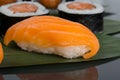On a black background with reflection, on a bamboo leaf, Japanese rolls with salmon and sushi, close-up