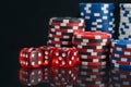 On a black background with reflection, pyramids of multi-colored poker chips and red dice, close-up Royalty Free Stock Photo