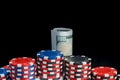 On a black background with a reflection, there are pyramids of colored chips and dollar bills wrapped in a roll for playing poker Royalty Free Stock Photo