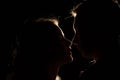 Black background, silhouette of couples, heads, between them a light, a ray of light unfinished kiss. the beginning of a kiss.
