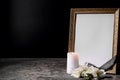 Blank funeral frame, candle and flowers on table against black background Royalty Free Stock Photo