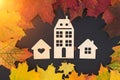 On a black background - three different wooden houses surrounded by autumn leaves. Concept - Autumn sales, year-end sales, Royalty Free Stock Photo