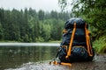 Black Backpack with Orange Straps by a Lake in a Forest Royalty Free Stock Photo