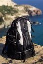 Black backpack on the rock peak over sea background