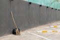 A black bag of garbage and old broom against a gray wall