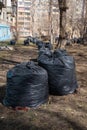 Black bags with garbage in the park, old fallen leaves, branches on the ground. A bunch of bags. Spring cleaning. Royalty Free Stock Photo