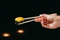 Black Baked roll in the Chinese chopsticks in hand Royalty Free Stock Photo