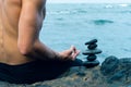 Balancing stones arranged in a pyramid shape with a back of a shirtless man meditating Royalty Free Stock Photo