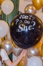 Black balloon with the words `he or she` baby gender disclosure party,