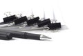 Black ballpoint pen in front of several stacks of paper held by binder clips