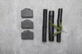 Black bamboo charcoal and  black soap bars with bamboo charcoal on grey background Royalty Free Stock Photo