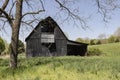 Black barn framed by trees.