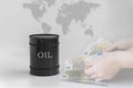 Black barrel with oil on the background of the world map, red graph down and hands that hold money.Grey simple background.The Royalty Free Stock Photo