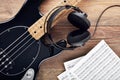 Black bass guitar with headphones and sheet music on wooden table Royalty Free Stock Photo