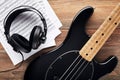 Black bass guitar with headphones and sheet music on wooden table Royalty Free Stock Photo