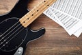 Black bass guitar with headphones and sheet music on wooden table Royalty Free Stock Photo