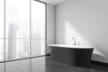 Black bathtub in the white panoramic bathroom interior. Corner view