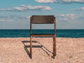 Black beach chair on empty sand beach with blue sea water background Minimalism style autumn travel relaxation No people