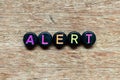 Black bead with letter in word alert on wood background