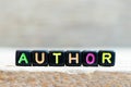 Black bead with letter in word author on wood background