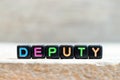 Black bead with letter in word deputy on wood background