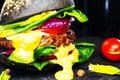 Black beef burger with flowing melted cheese on a black background. Close-up. Royalty Free Stock Photo