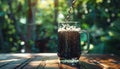 Black beer pouring into mug in nature background