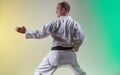 Black belt athlete doing formal exercises against a colored background with yellow and green tints Royalty Free Stock Photo