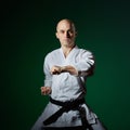 With a black belt, an athlete trains formal karate exercises on a dark green background Royalty Free Stock Photo