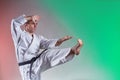 Black belt trainer performing formal exercises against a colored background with red and green tints Royalty Free Stock Photo