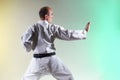 A black belt trainer performs formal exercises against a colored background with yellow and green tints Royalty Free Stock Photo