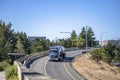 Black big rig bonnet semi truck with tank semi trailer transporting liquid cargo turning on the overpass road to highway entrance Royalty Free Stock Photo