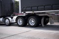 Black big rig semi truck with chrome wheels and fenders and black tented frame semi trailer going by roadway Royalty Free Stock Photo