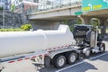 Black big rig semi truck tractor transporting tank semi trailer with chemical toxic substances running under the bridge on the Royalty Free Stock Photo