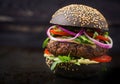 Black big sandwich - black hamburger with juicy beef burger, cheese, tomato, and red onion Royalty Free Stock Photo