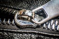 Black big zipper on leather material with shiny metal head in closeup photo