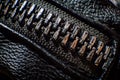 Black big zipper on leather material with shiny metal head in closeup photo