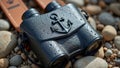 Black binoculars with anchor design on pebbled beach Royalty Free Stock Photo
